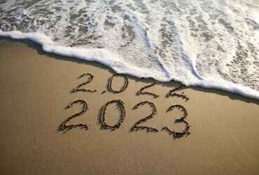 New year 2023 and old year 2022 written on sandy beach with waves