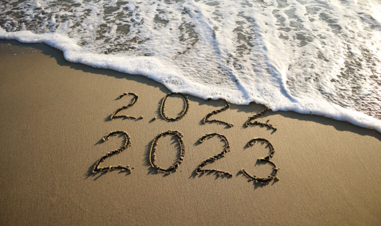 New year 2023 and old year 2022 written on sandy beach with waves