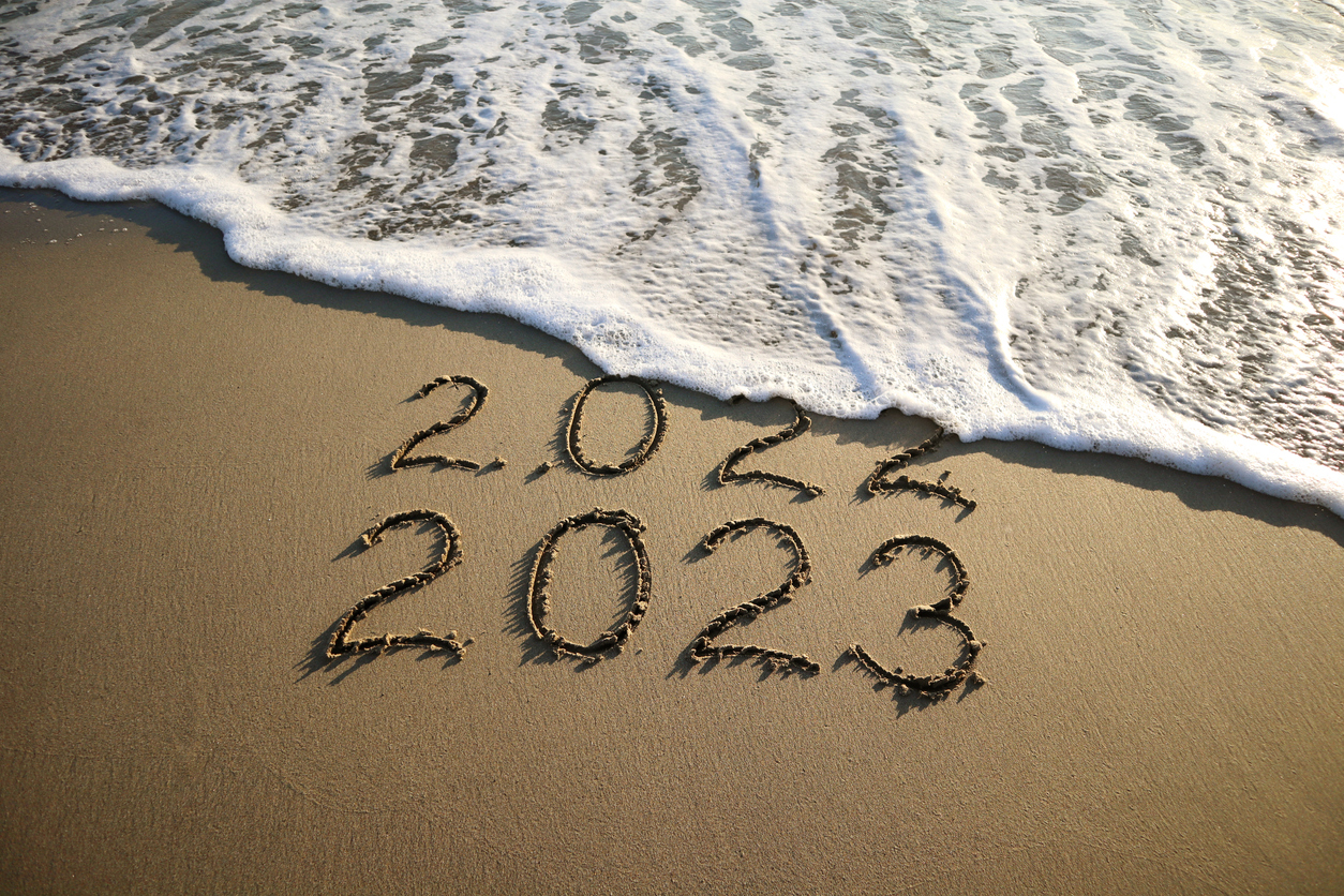 New year 2023 and old year 2022 written on sandy beach with waves