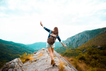 Young woman taking a walk on top of a mountain and enjoying the day