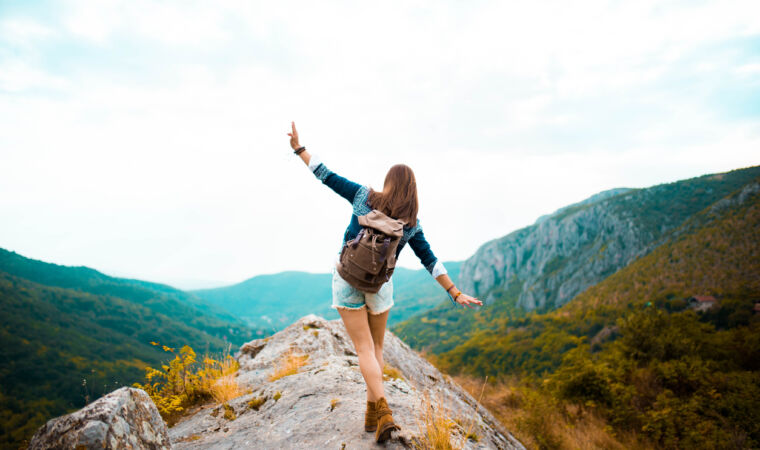 Young woman taking a walk on top of a mountain and enjoying the day